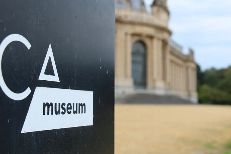 Sign for the AfricaMuseum in Tervuren, Belgium, with the museum building blurred in the background. ©Tervuren+
