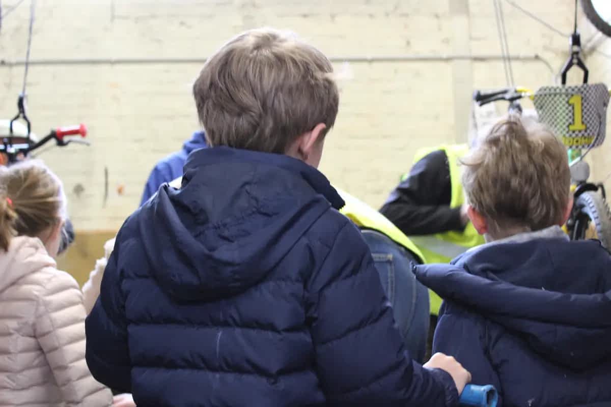 Kinderen wachten op laatste fietscontrole door vrijwilligers Fietsbieb Tervuren